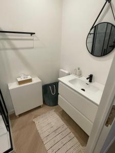 Un baño blanco con lavabo y espejo. en Stadsstudio op toplocatie, en Amberes