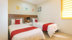 a bedroom with two beds with red and white sheets at RedDoorz @ Leoncia Apartelle Mandaue City in Mandaue City