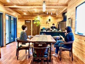 a group of people sitting at a table in a kitchen at 紬の宿こがち -奄美大島の貸切別荘- kogachi japanese kominka stay in Amami Island in Tatsugo