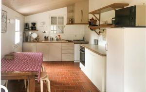 una cucina con armadietti bianchi e pavimento in mattoni rossi di Nice Home In La Boissière Des Lande a La Boissière-des-Landes Altre 12 foto