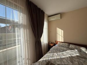 a bedroom with a bed and a large window at GRAND APARTMENT BOGORIDI - top center near to sea and sea garden in Burgas City +130 photos