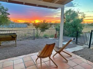 a couple of chairs sitting on a patio with a sunset at Lazy H Bar Desert Outpost Ranch House with Pool and Hot Tub in Tucson
