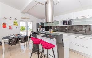a kitchen with white cabinets and red bar stools at Lovely Home In Brodarica With Jacuzzi in Brodarica