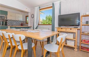a dining room with a table and chairs and a tv at Holiday Home Mravnica 09 in Mravnica