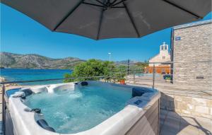 a hot tub on a patio with an umbrella at Awesome Home In Kneze in Pupnat