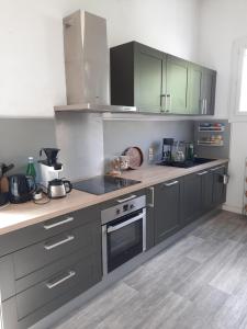 a kitchen with gray cabinets and a stove top oven at Maisonnette pour halte angevine in Les Ponts-de-Cé