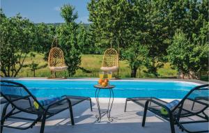 two chairs and a table next to a swimming pool at Three-Bedroom Holiday Home In Prolozac Donji in Donji Proložac