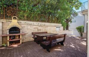 een picknicktafel en een bankje naast een bakstenen muur bij Gorgeous Apartment In Crikvenica in Crikvenica +18 foto's