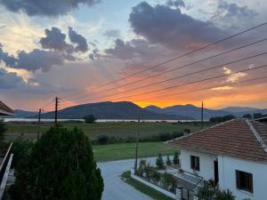 a sunset over a house with mountains in the background at Ourania's Apartment Kastoria in Mavrokhórion