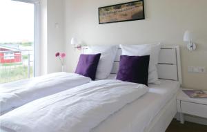 a bedroom with two white beds with purple pillows at Nice Home In Dagebüll With Sauna in Dagebüll