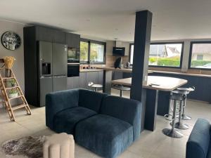 a living room with a blue couch and a kitchen at Maison avec toit terrasse in Villers-sur-Mer