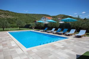een zwembad met blauwe stoelen en parasols bij Villa Sara Family Villa with Pool and Jacuzzi Imotski Makarska Region in Imotski