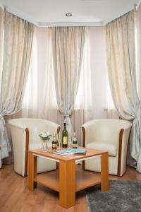 a living room with two white chairs and a table at Sin-Kom Hotel Garni in Pirot