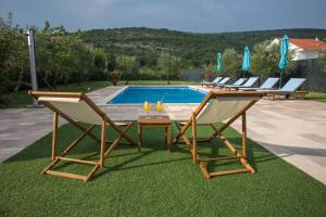 een groep stoelen en een tafel naast een zwembad bij Villa Sara Family Villa with Pool and Jacuzzi Imotski Makarska Region in Imotski