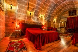 a bedroom with a red bed in a stone wall at Kapadokya Ihlara Konaklari & Caves in Guzelyurt