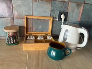 a cup of coffee next to a box of utensils at Funky appartment in Zaječar