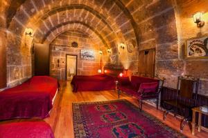 a bedroom with two beds in a room with a stone wall at Kapadokya Ihlara Konaklari & Caves in Guzelyurt