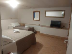 Una habitación de hotel con dos camas y un televisor. en Garden Basement - Seminterrato Max 4 Ospiti - Fiumicino vicino Aeroporto e Fiera, en Fiumicino