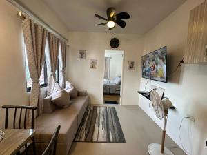 een woonkamer met een bank en een plafondventilator bij Cozy Condo Almond drive 1BR Talisay SRP w pool in Tangke