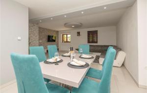 a dining room with a white table and blue chairs at Nice Home In Vinjani Donji in Donji Vinjani
