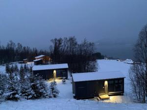 a building in the snow with lights on at Northern Light Cottage in Ytre Tomasjord