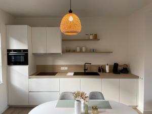 a kitchen with white cabinets and a table with chairs at Pand 43 in Diksmuide
