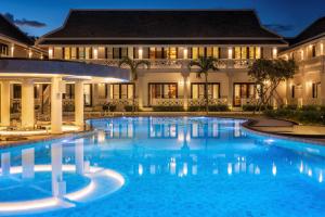 a swimming pool in front of a building at night at Choasis Hotel-Luang Prabang in Luang Prabang