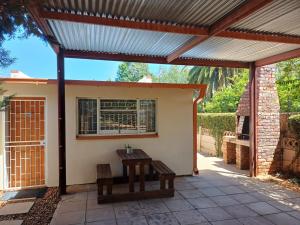 a pergola with a bench on a patio at Susanna's Self catering 2 bedroom apartment in Kimberley