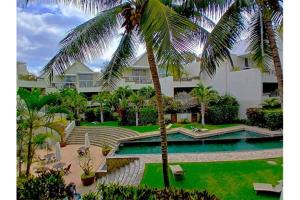 a palm tree in front of a building with a swimming pool at Seaside 3 suites Penthouse with Pool Gym & BBQ Terrace in Cap Malheureux