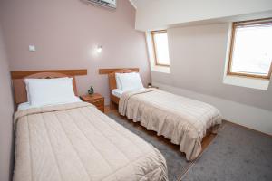 two beds in a room with two windows at Sin-Kom Hotel Garni in Pirot