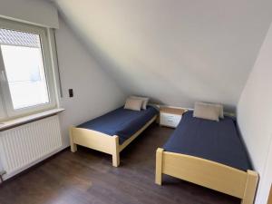 two beds in a small room with a window at Bovenappartement in Winterberg met balkon en uitzicht over het bos in Winterberg