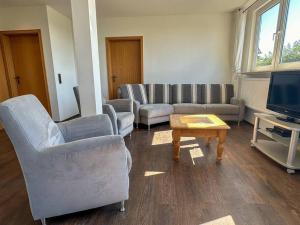 a living room with couches and a tv and a table at Bovenappartement in Winterberg met balkon en uitzicht over het bos in Winterberg