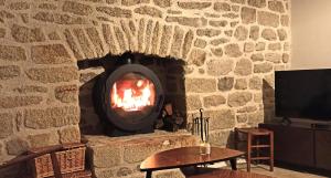 a stone fireplace with a fire in it at Charmante longère bigoudène in Penmarch