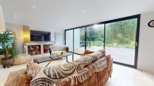 a living room with a couch and a large window at La Cachette des Vagues in Les Sables-dʼOlonne