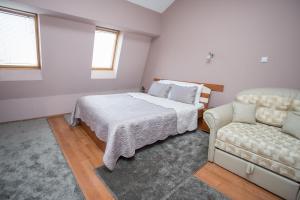a bedroom with a bed and a couch at Sin-Kom Hotel Garni in Pirot