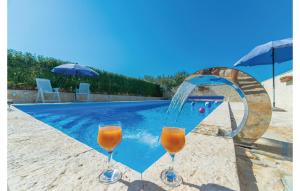 2 vasos de zumo de naranja junto a la piscina en Beautiful Apartment In Vrana With Wifi, en Vrana