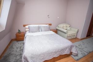a bedroom with a white bed and a chair at Sin-Kom Hotel Garni in Pirot