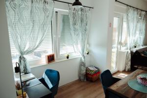 a living room with windows and a table and chairs at Studio apartman Ars libri in Đakovo