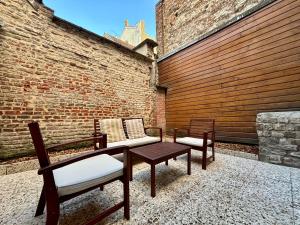a patio with two chairs and a table and a brick wall at Le Petit Hainaut, hyper centre in Valenciennes
