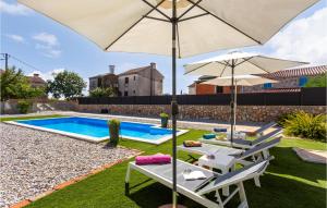 a pool with two chairs and an umbrella at 2 Bedroom Pet Friendly Home In Brzac in Brzac