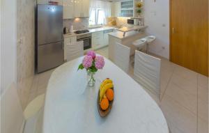 une table blanche avec un vase de fleurs et de fruits sur elle dans l'établissement Cozy Home In Plat With Wifi, à Mlini