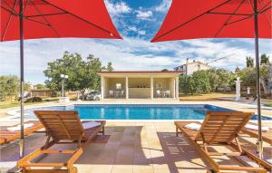 - une piscine avec deux chaises et deux parasols rouges dans l'établissement Apartment Peroj Ii, à Vodnjan