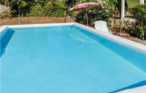 a large blue swimming pool with an umbrella and two chairs at Lovely Home In Xativa-Almaseretes in Caserío Casa Sanchis