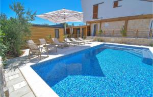 Una piscina con sillas y una sombrilla al lado de una casa. en Lovely Home In Brodarica, en Brodarica