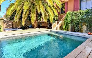 a swimming pool in front of a house with a palm tree at Lovely Apartment In Pujaut With Wifi in Pujaut