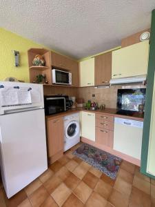 una cocina con refrigerador y lavadora y secadora en Appt T2 à Saint-Lary-Soulan à 100m du centre, en Saint-Lary-Soulan