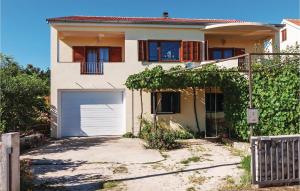 a white house with a garage and a fence at One-Bedroom Apartment In Maslenica in Maslenica