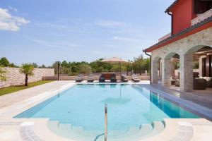 a swimming pool with chairs and a building at Residence Monaco for 10 people in Central Istria with 65 m2 private pool, large garden & spa in Svetvinčenat