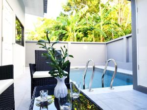 eine Terrasse mit Tisch und Stühlen und einem Pool in der Unterkunft Calm & Cozy Vacation House in Rawai Beach