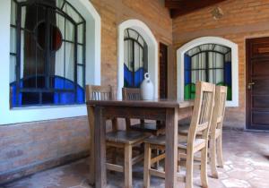 a wooden table and chairs on a patio with windows at Posada Argimon in San Marcos Sierras +27 photos